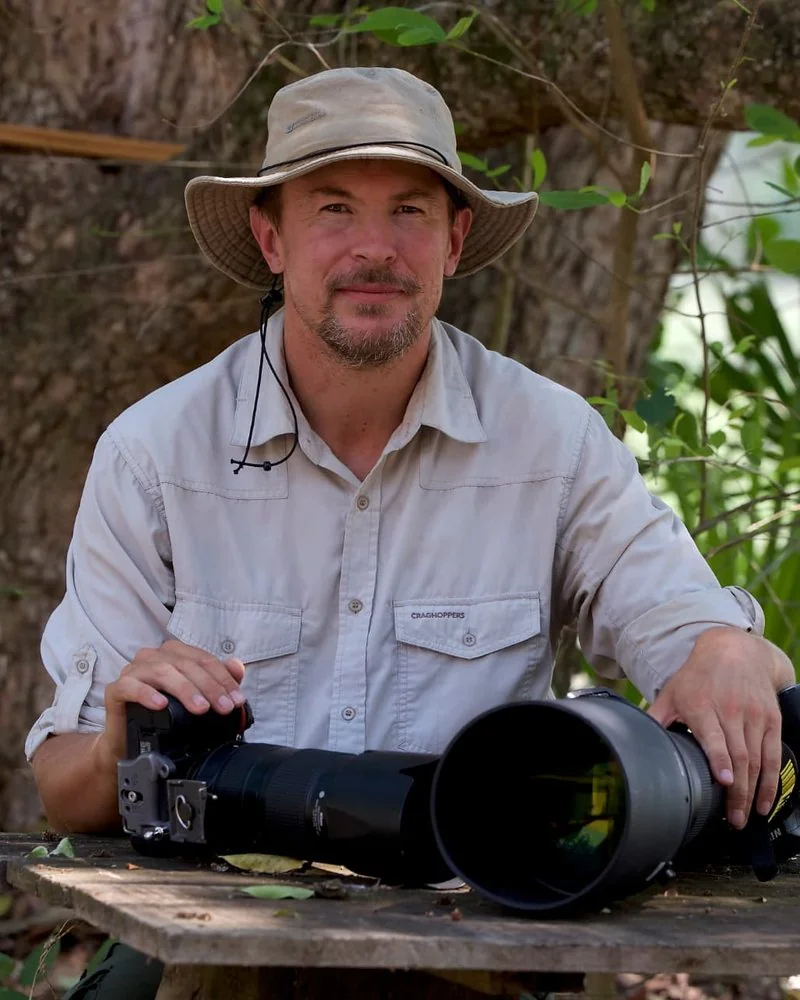 Nick Dale seated with his camera equipment in woodland